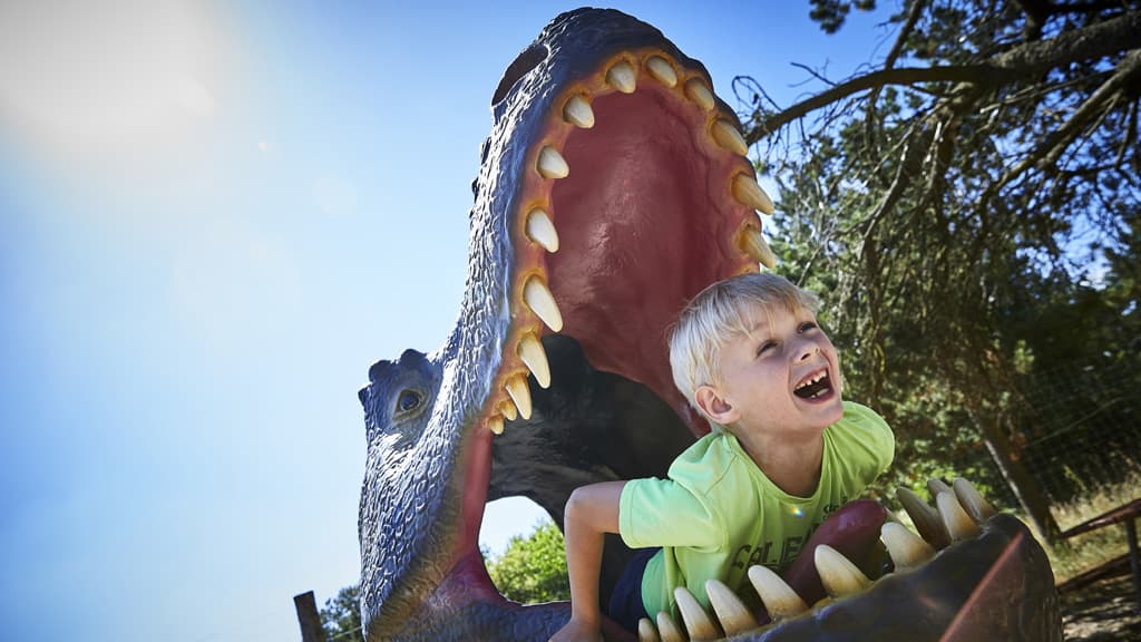 Kind im Maul eines Dinosauriers
